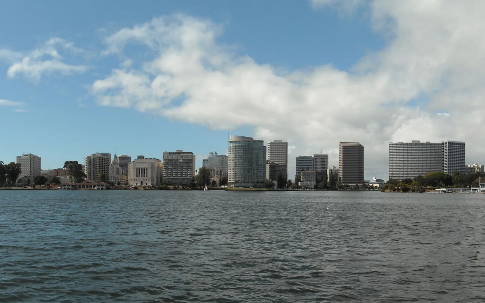 The Oakland skyline reflecting in Lake Merritt, with downtown buildings and a clear sky
